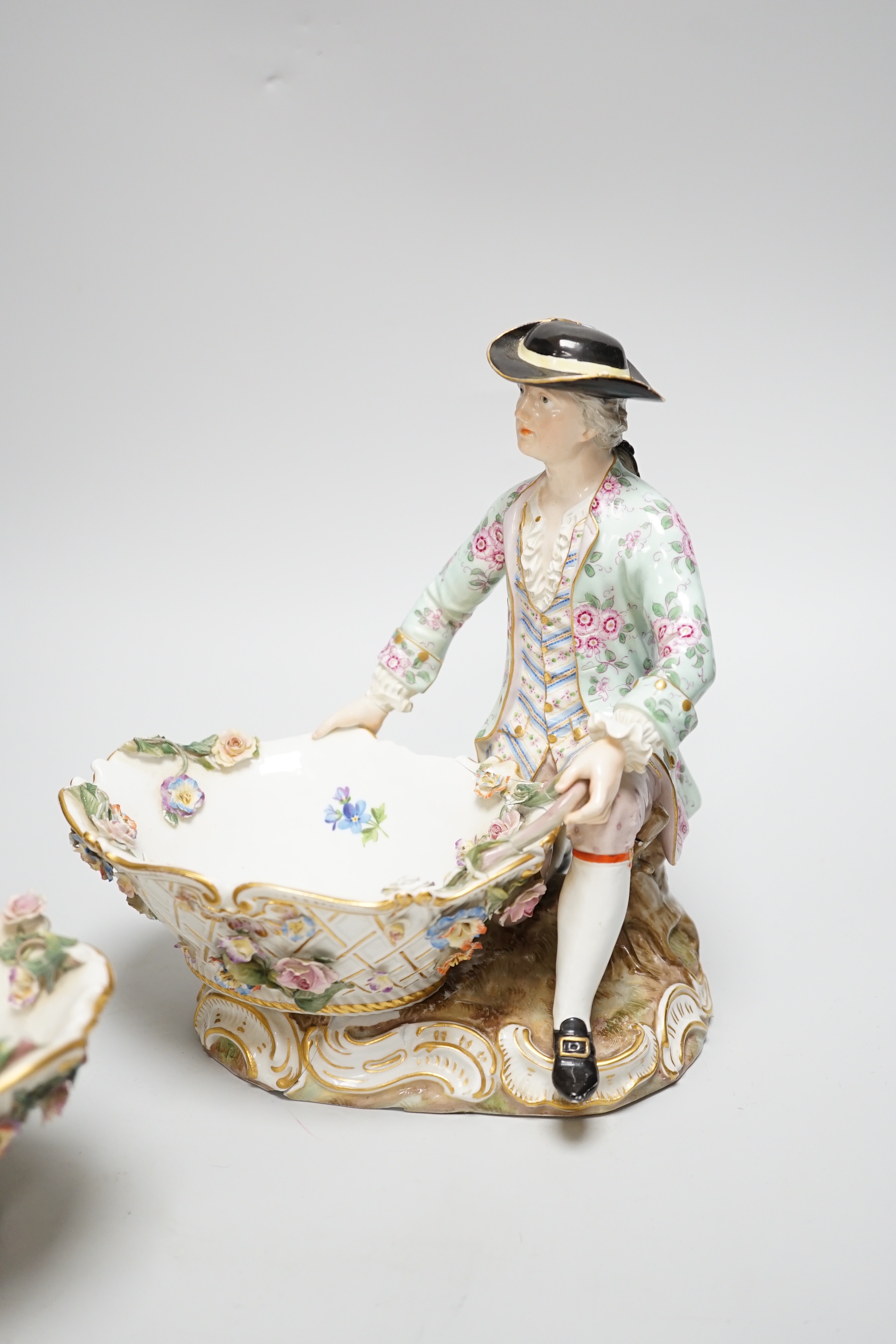 A large pair of Meissen salts in the form of a seated man and a woman in 18th century dress (a.f.), 21cm high
